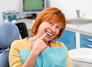Excited woman pointing at her new implant denture