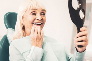 Senior woman admiring her smile after receiving partial denture