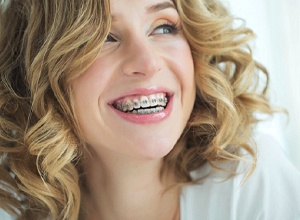 Smiling young woman with traditional braces in Newington