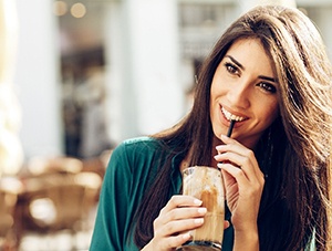 Woman with beautiful teeth sipping coffee through straw