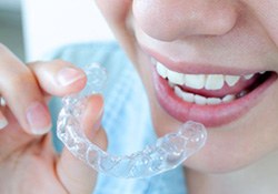 Woman preparing to place Invisalign tray on her teeth