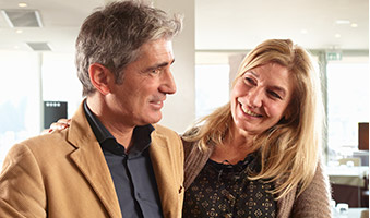 Smiling man and woman at front desk in Newington dental office