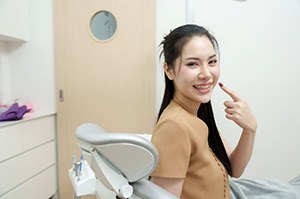 Happy dental patient pointing at her smile