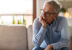 Thinking senior man sitting on sofa