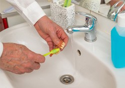 Person using brush to clean their dentures