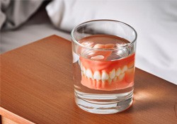 Dentures in cup of water on nightstand