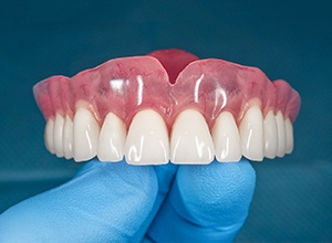 close-up of gloved hand holding full upper denture