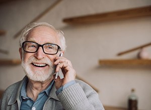 Smiling senior man holding phone to his ear