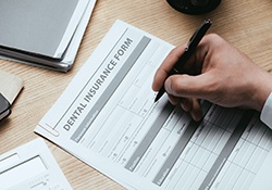 Man’s hand using pen to fill out dental insurance form