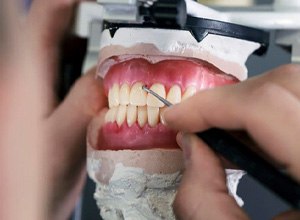 Dental lab technician putting the final touches on dentures