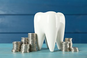 Tooth model next to coins, representing cost of emergency dentistry