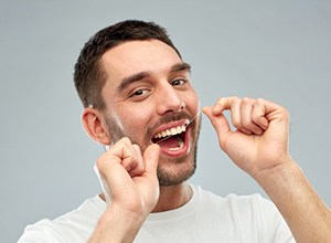 Man flossing to prevent dental emergencies in Newington