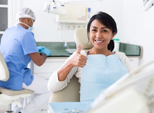 Patient giving thumbs up after successful dental implant salvage