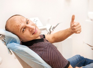 Dental patient giving thumbs up after successful implant salvage