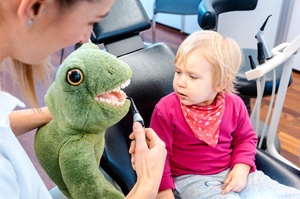 Little toddler in dentist’s office being taught about oral health