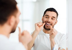 Young man in white t-shirt flossing his teeth