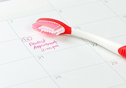 Dentist appointment marked on calendar next to red and white toothbrush