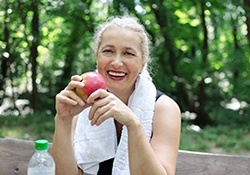 woman with dental implants in Newington eats an apple