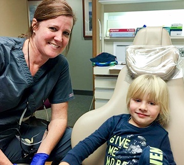 Dental team member and young boy in dental room