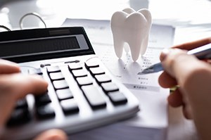 Using pen and calculator to budget for dental treatment