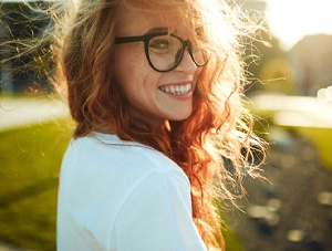 Smiling woman in glasses enjoying benefits of tooth-colored fillings