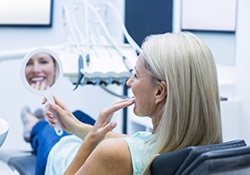 Happy patient admiring the results of her cosmetic dentistry treatment