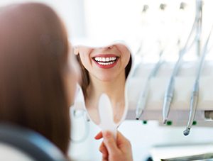 Dental patient admiring bright new smile in mirror