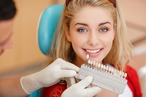 Woman’s bright smile next to dental shade guide