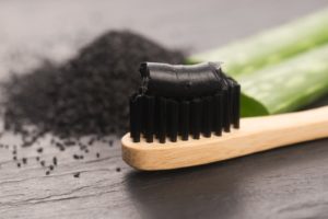 activated charcoal toothpaste on toothbrush with black bristles