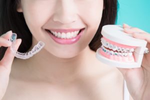 Woman holding traditional braces and Invisalign in Newington