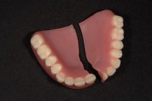 Broken full denture in Newington against black background