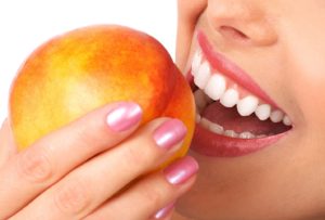 Woman with veneers in Newington eating a peach
