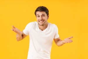Puzzled man in white t-shirt against yellow background
