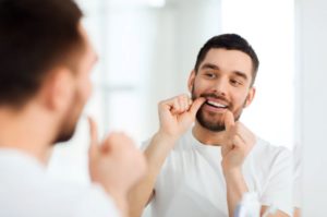Man in front of mirror, flossing