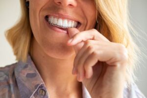 Close-up of woman’s mouth as she places Invisalign aligner on her