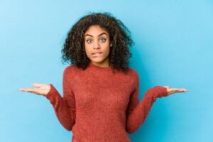 Shrugging woman wearing confused expression 
