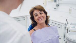 Middle-aged dental patient smiling at her dentist 